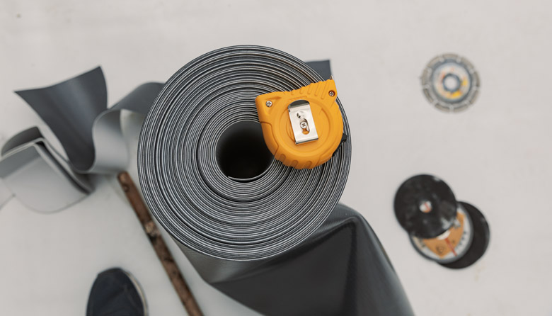 Thermoplastic Polyolefin (TPO) membrane rolled up with an orange tape measure on top