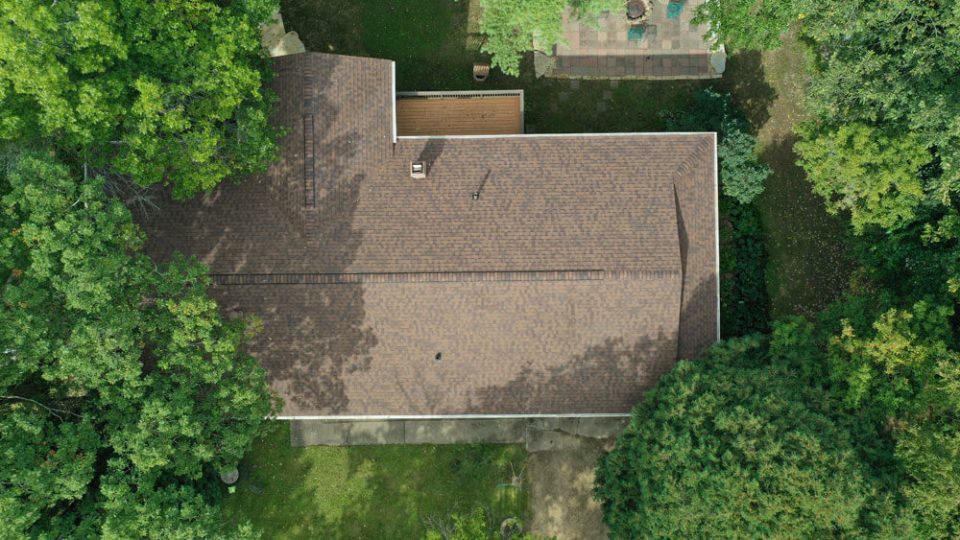 Aerial view of a home after a newly replaced roof with brown asphalt shingles