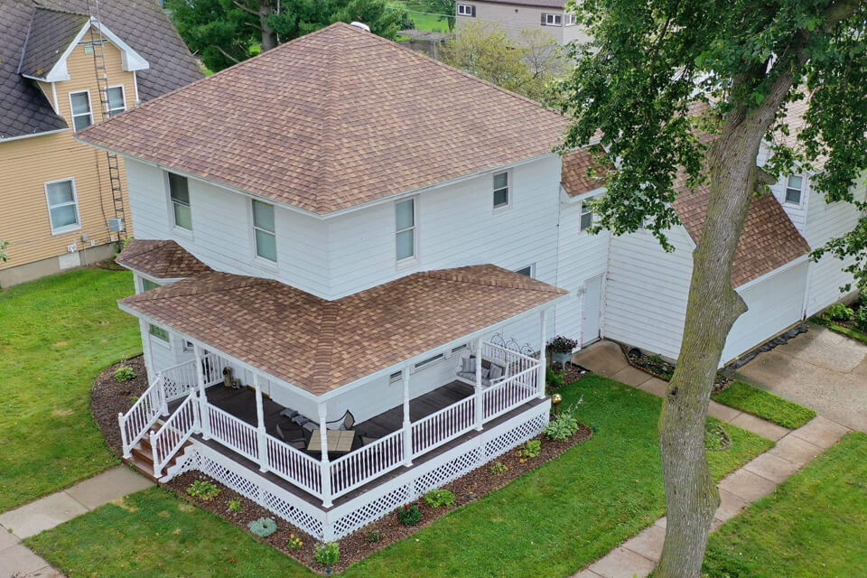 View from above of a 2-story white house with brown asphalt shingles
