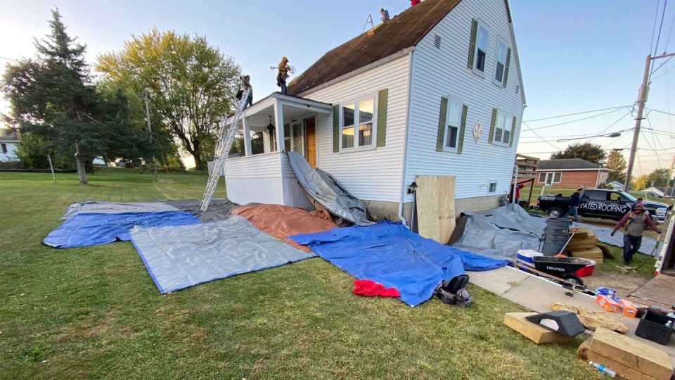 Elizabeth, IL house #2 during roof replacement; roofers lay tarps to protect surrounding area
