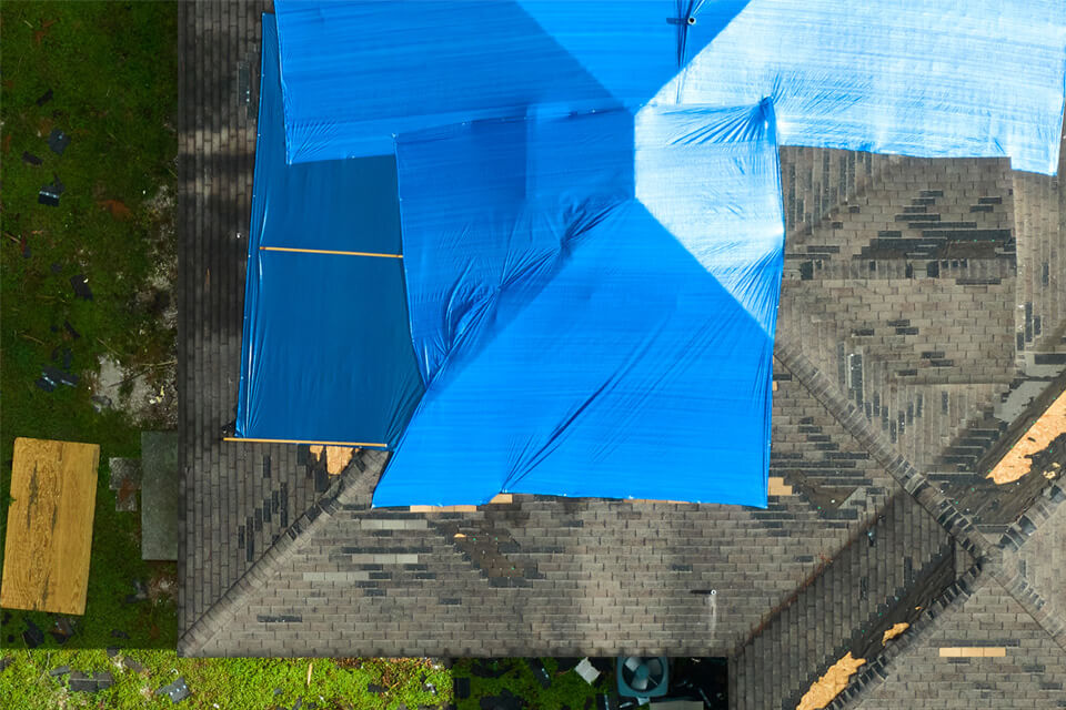 Aerial view several blue tarps covering an unfinished rooftop