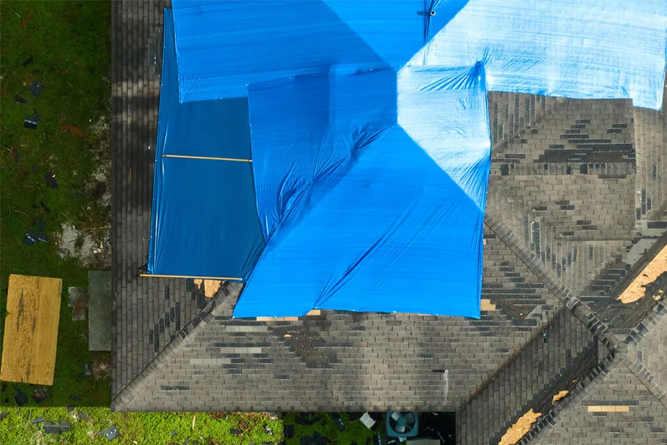 Aerial view several blue tarps covering an unfinished rooftop