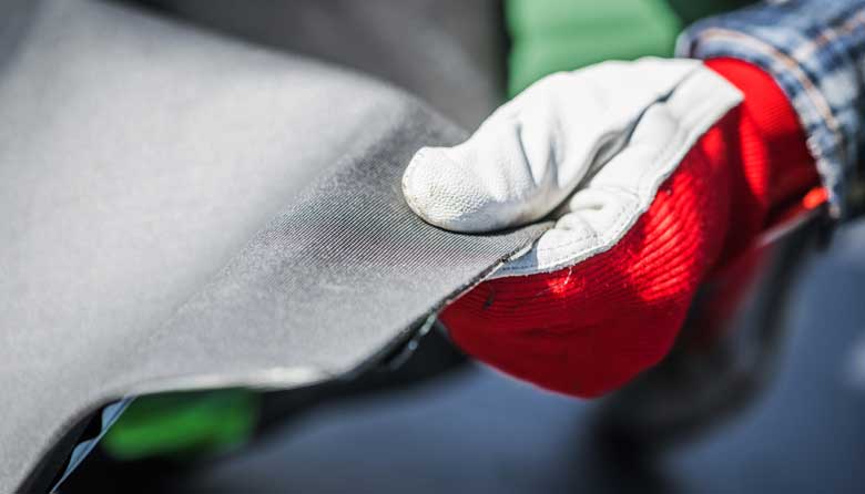 Close up of a hand wearing a red and white glove holding Ethylene Propylene Diene Terpolymer material