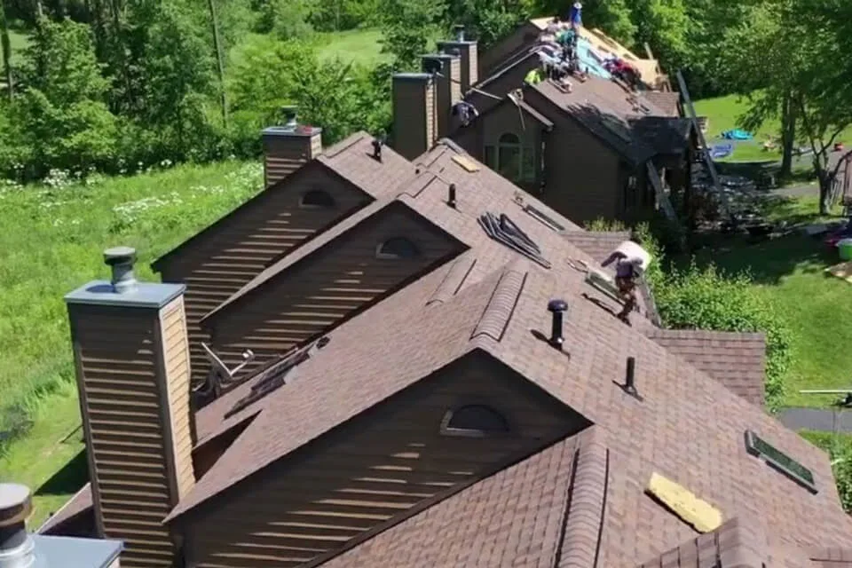 View of the rooftops of multifamily homes, with roofers performing a full roof replacement