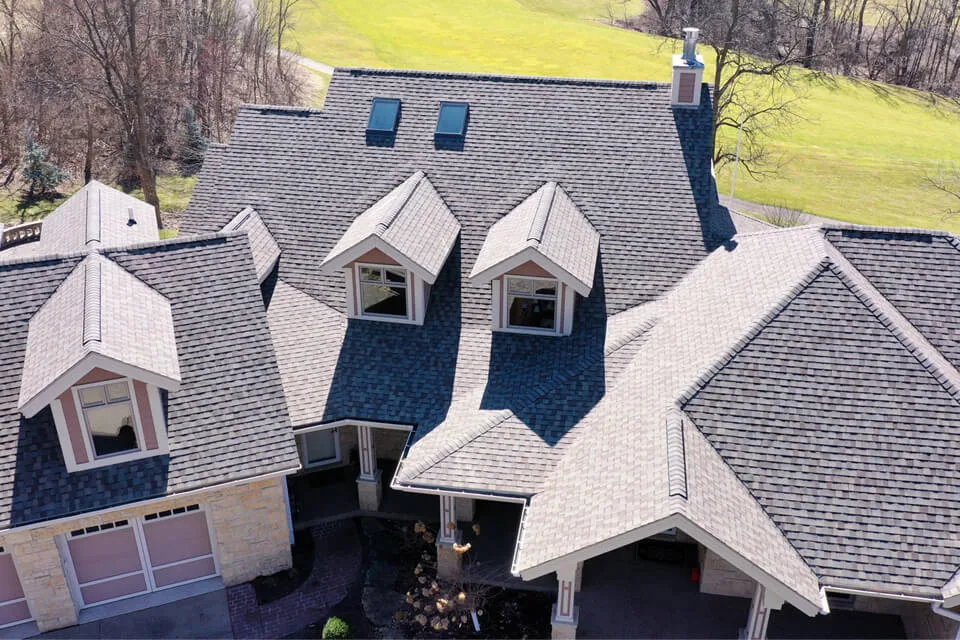 Aerial view of a large home with dormers and skylights after a roof replacement