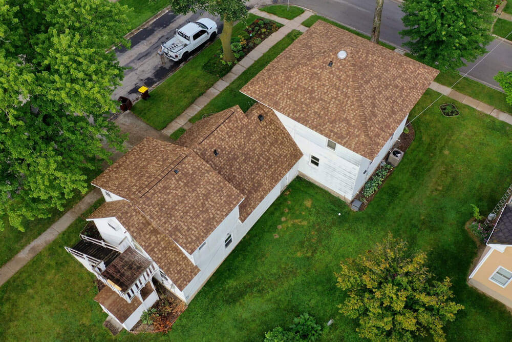 Close up of a roof after a full replacement, showing new charcoal asphalt shingles and flashing